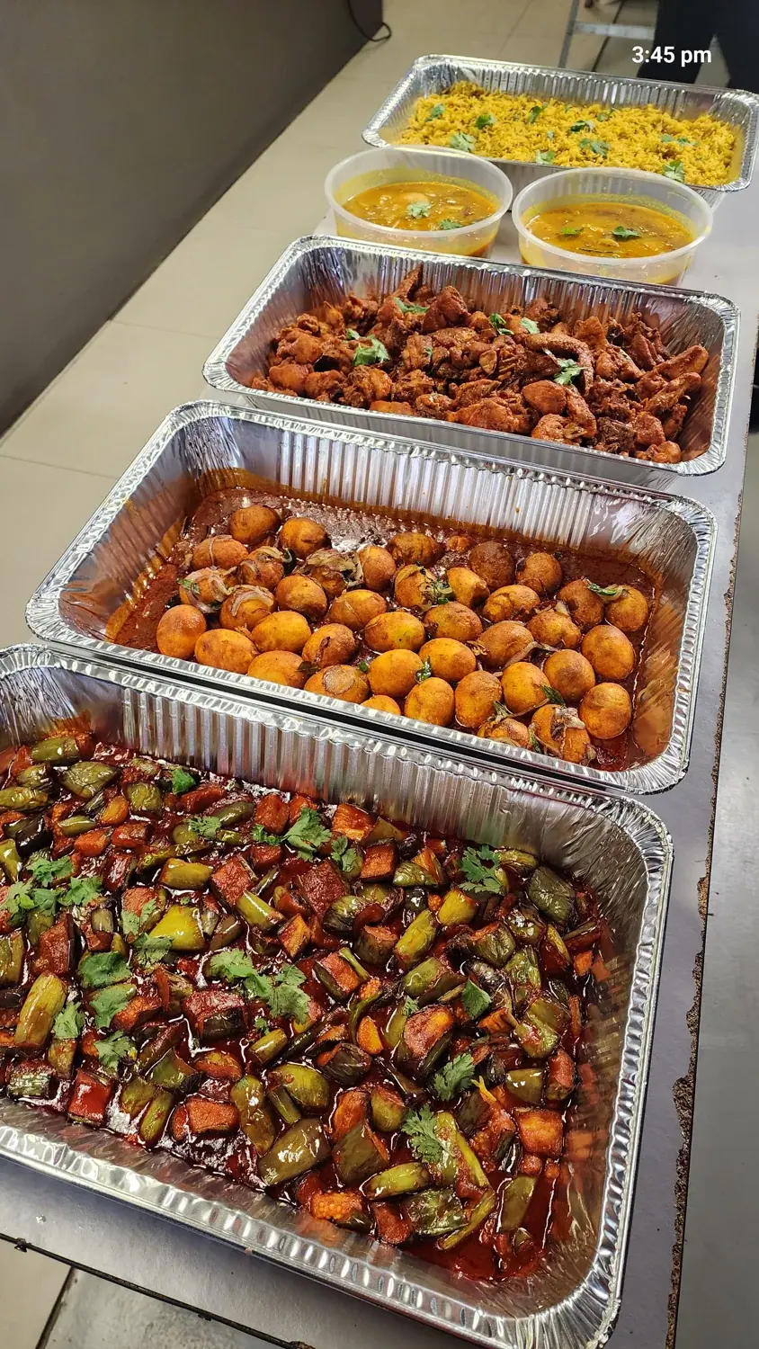 A row of disposable catering trays filled with dishes
