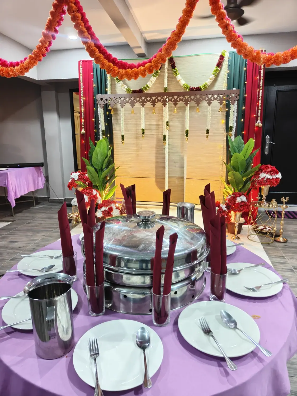 Chafing dishes and table settings beside colourful traditional decorations